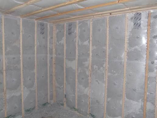 Framed stud walls filled with blown insulation held behind mesh netting